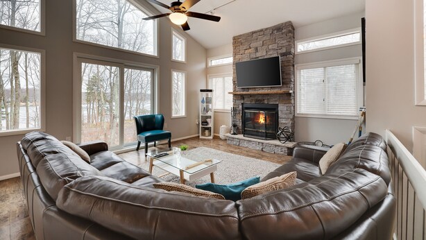 A spacious living room with a leather sofa, a glass coffee table, and a fireplace.