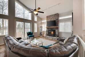 A spacious living room with a leather sofa, a glass coffee table, and a fireplace.