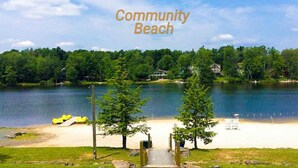 A community beach with a clear view of the lake, a sandy shore, and a few yellow paddle boats.