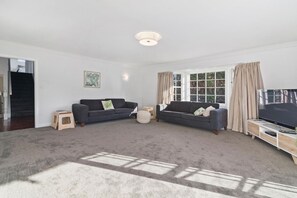 A living room with two sofas, a television, and a window with curtains. - Thermal Adventure - Plunge Pool, Sleeps 11 (Rotorua)