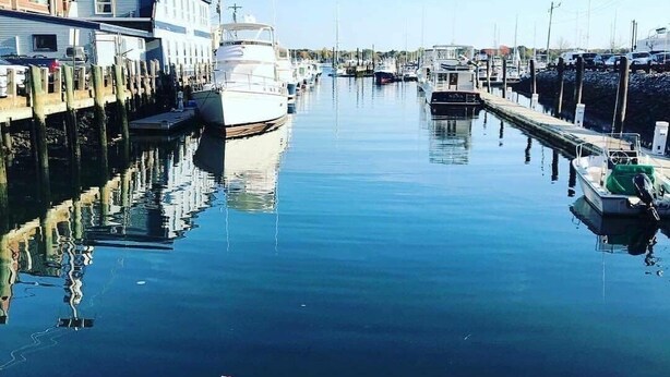 A marina with boats docked along the water, a docked boat in the foreground, and buildings on the left side. - The coast of Maine a spacious 10 bedroom home. Equipped with an in ground pool (Saco)