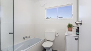 Une salle de bain avec une baignoire, des toilettes et une fenêtre.
