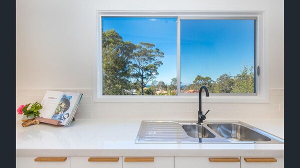 Una cocina con ventana, un lavabo y una revista sobre la encimera.