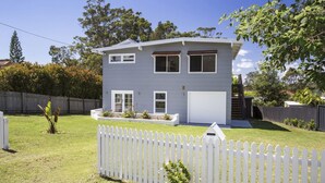 A two-story house with a garage, a fenced yard, and a small garden. - Arthurs in Mollymook (Mollymook Beach)