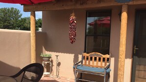 A patio area with a wooden bench, a table, and a red umbrella. - Charming Casita in historic Town of Mesilla,  NM  2392 Calle de Parian (Mesilla)