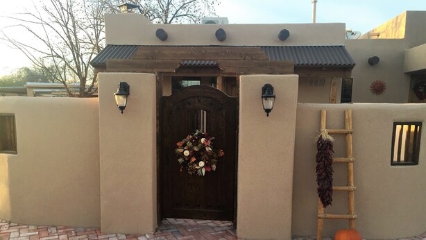 A building entrance with a wooden door, a brick pathway, and a decorative wreath. - Charming Casita in historic Town of Mesilla,  NM  2392 Calle de Parian (Mesilla)