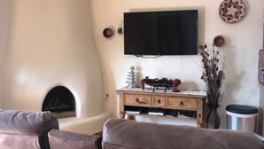 A living room with a fireplace, a television mounted on the wall, and a ceiling fan. - Charming Casita in historic Town of Mesilla,  NM  2392 Calle de Parian (Mesilla)