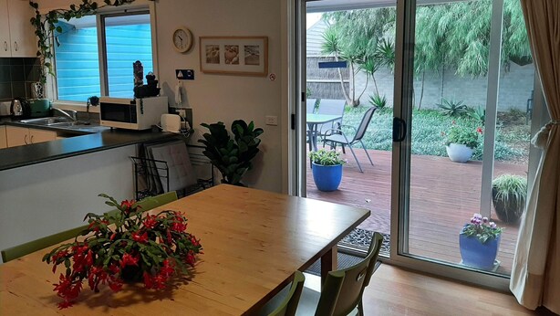 Cocina moderna con comedor, puerta corrediza de vidrio a un patio y un reloj en la pared.