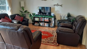 Una sala de estar con sofás de cuero, una estantería, un televisor de pantalla plana y decoración de peces en la pared.
