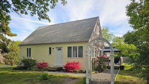 A single-story house with a front porch, a covered outdoor seating area, and a well-maintained garden with flowering plants. - Oak Bluffs - Quiet neighborhood (Oak Bluffs)