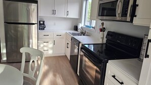 A modern kitchen with white cabinetry, stainless steel appliances, and a black stove. - Oak Bluffs - Quiet neighborhood (Oak Bluffs)