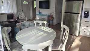 A modern kitchen with a stainless steel refrigerator, a dining table with chairs, a sofa, and a television mounted on the wall. - Oak Bluffs - Quiet neighborhood (Oak Bluffs)