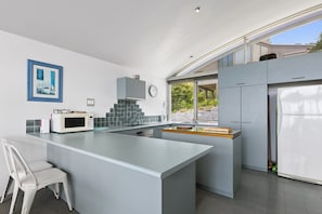 A modern kitchen with a central island, a microwave, and a sink. - Magnum (Lorne)