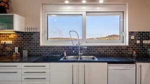 A modern kitchen with a large window, a built-in sink, and a dishwasher. - Spacious Family Villa, Private pool,  beach 5 km (Filaki)
