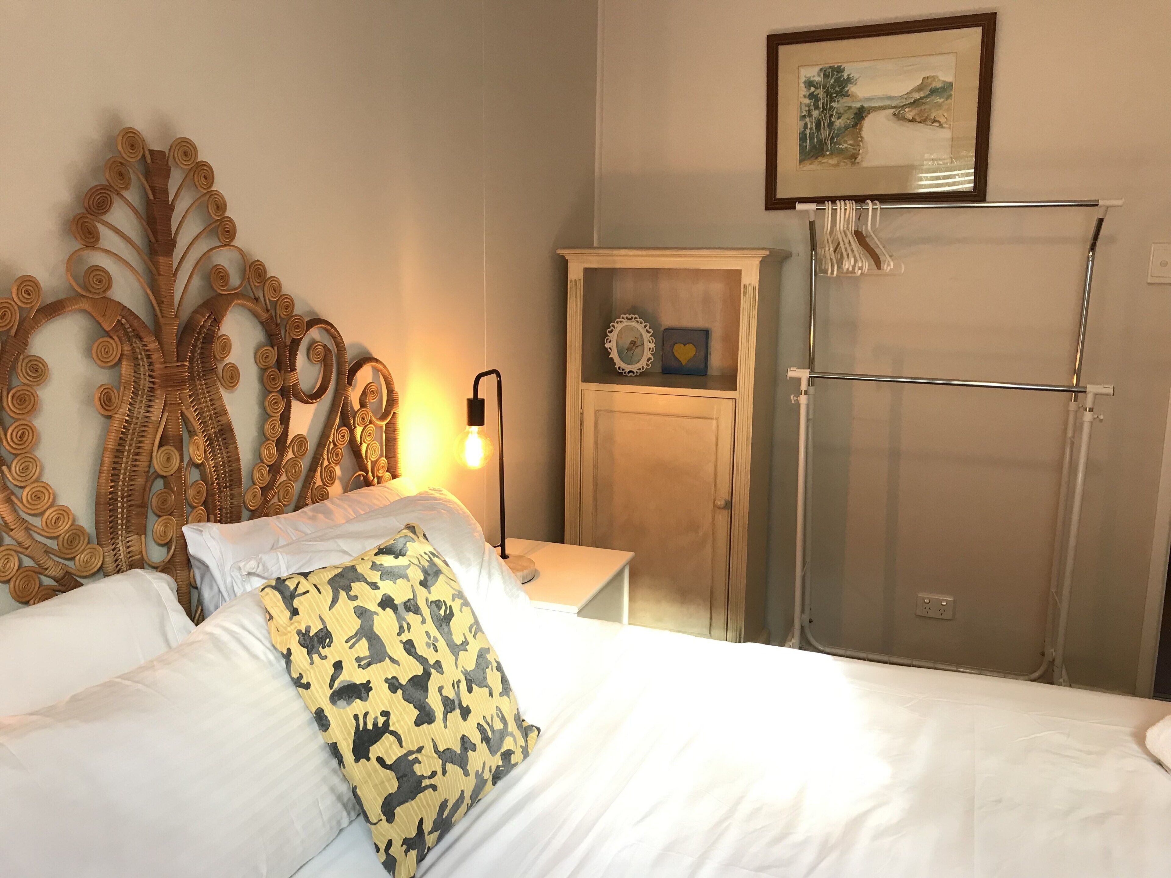 A bedroom with a bed, a wall-mounted light, a wardrobe, and a framed picture on the wall.