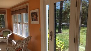 Ein Zimmer mit einer Schiebetür zum Garten, Korbmöbeln und einem gerahmten Bild an der Wand.