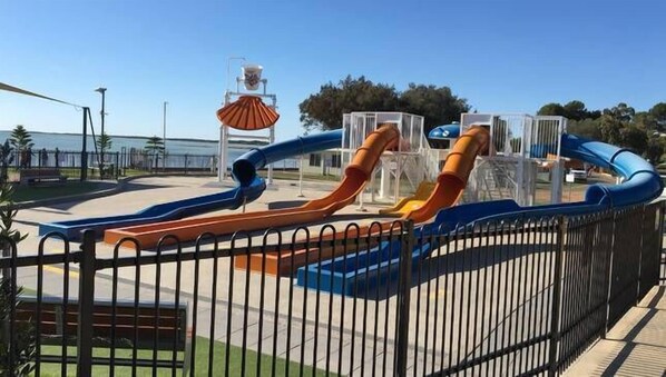 Un parque infantil con toboganes y una zona vallada.