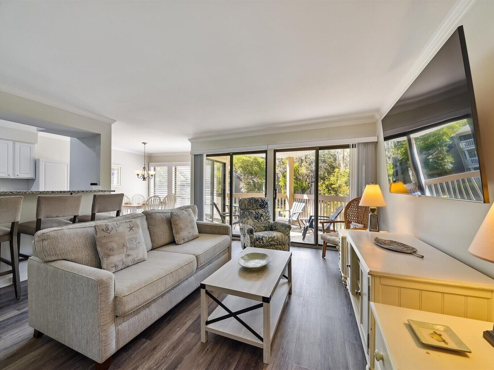 A spacious living area with a sofa, coffee table, and a balcony with outdoor seating.