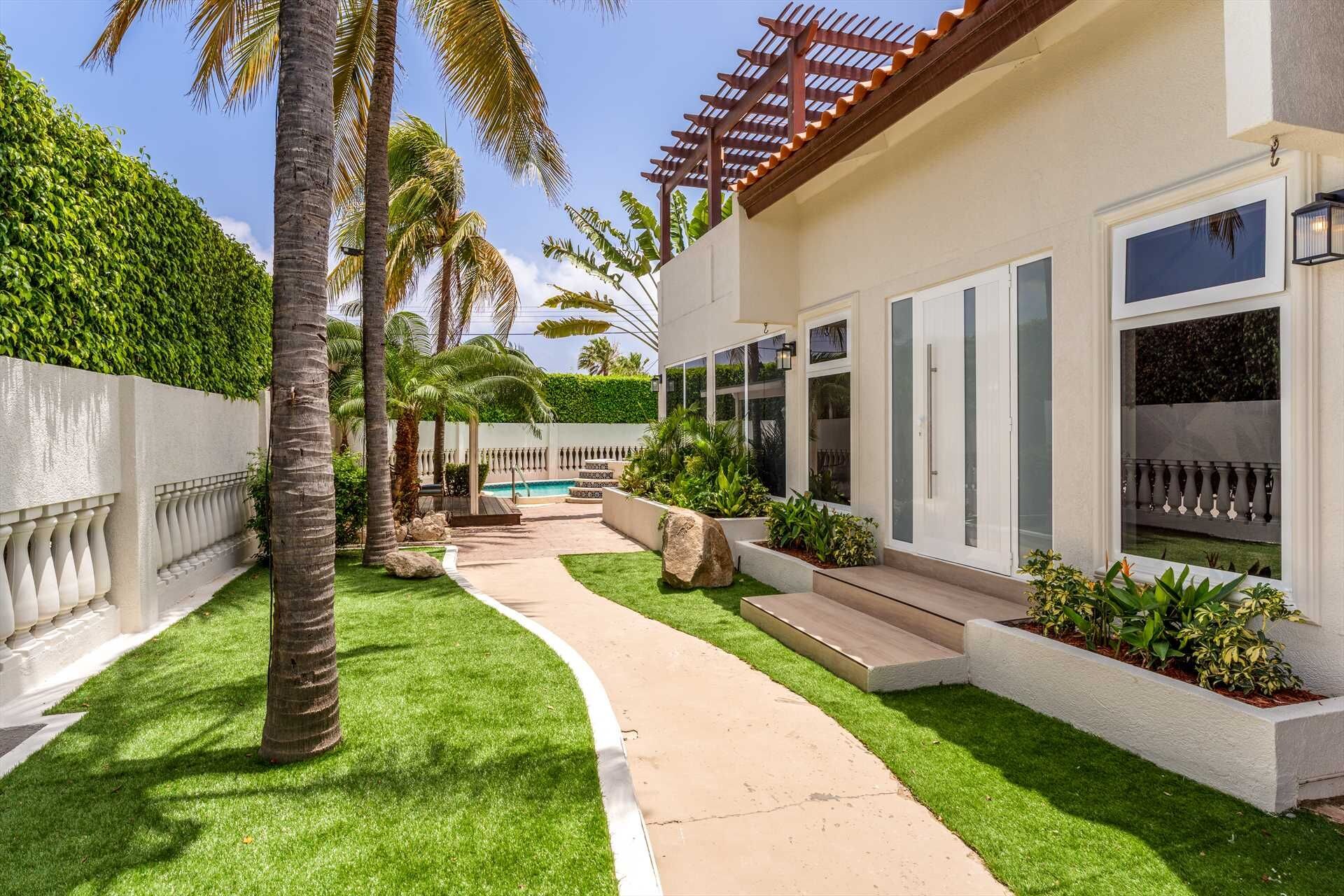 Une maison moderne avec une piscine, entourée de pelouses bien entretenues et de palmiers.