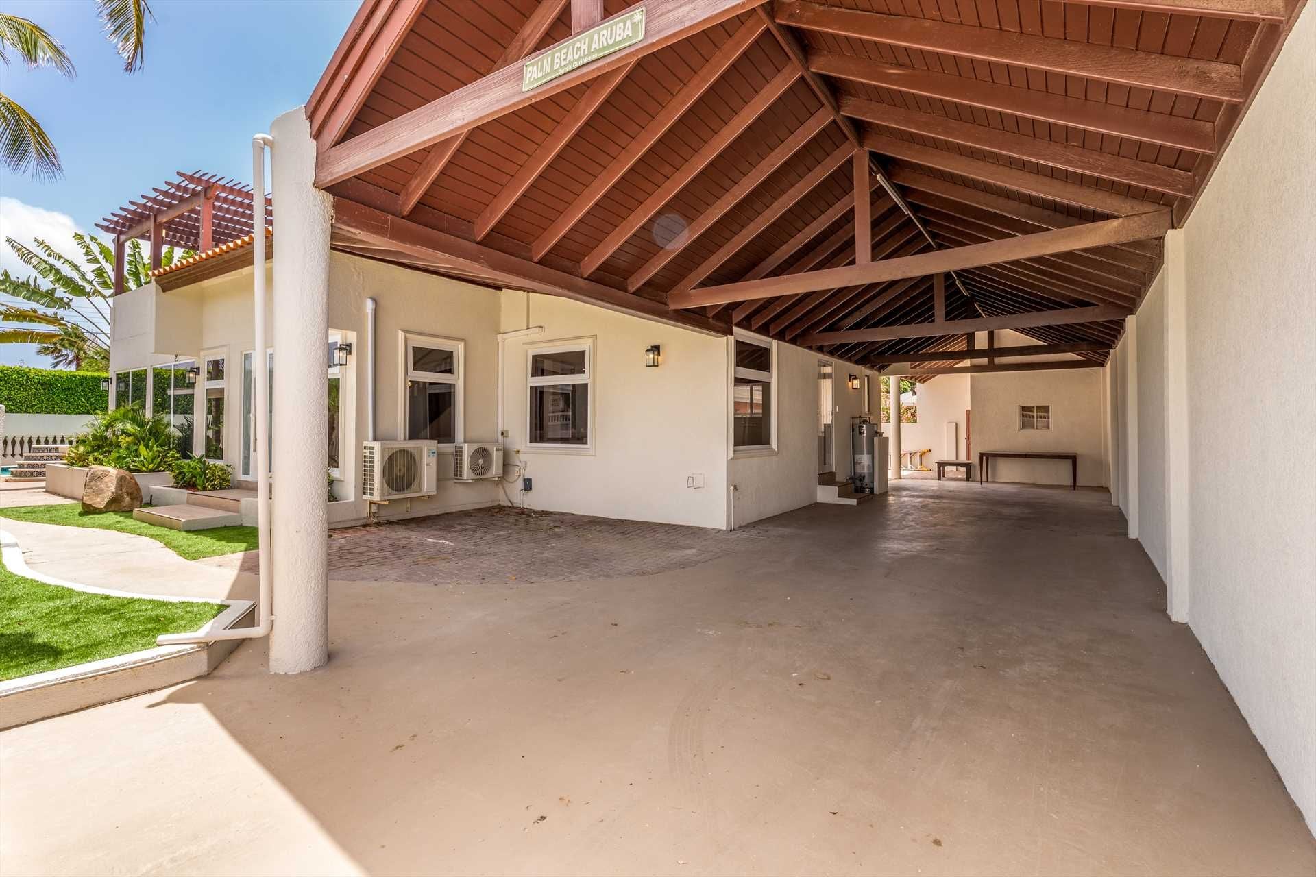 Un espace extérieur abrité, agrémenté d’un palmier, d’une pergola et d’un panneau indiquant « Palm Beach Aruba ».