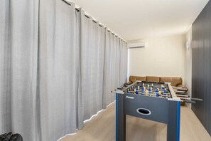 Een kamer met een tafelvoetbaltafel, een bank en gordijnen.