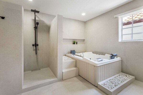 A modern bathroom with a walk-in shower, a freestanding bathtub, and a window providing natural light.