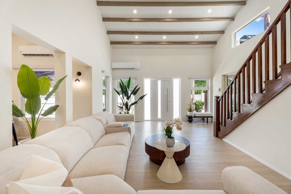 A spacious living area with a sofa set, a coffee table, and a staircase.