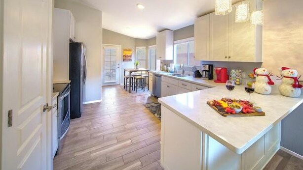 Una cocina moderna con una isla central, suelo de madera e iluminación colgante.