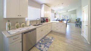 Una cocina moderna con armarios blancos, lavavajillas y una isla central.