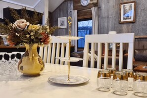 A dining table with a vase of flowers, a tiered serving tray, and several glasses.