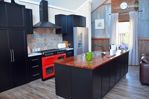 A kitchen with black cabinets, a red stove, and a wooden island with a green vase.