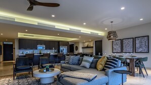 Una sala moderna con un sofá seccional gris, una mesa de centro y un comedor con una mesa y sillas de madera.