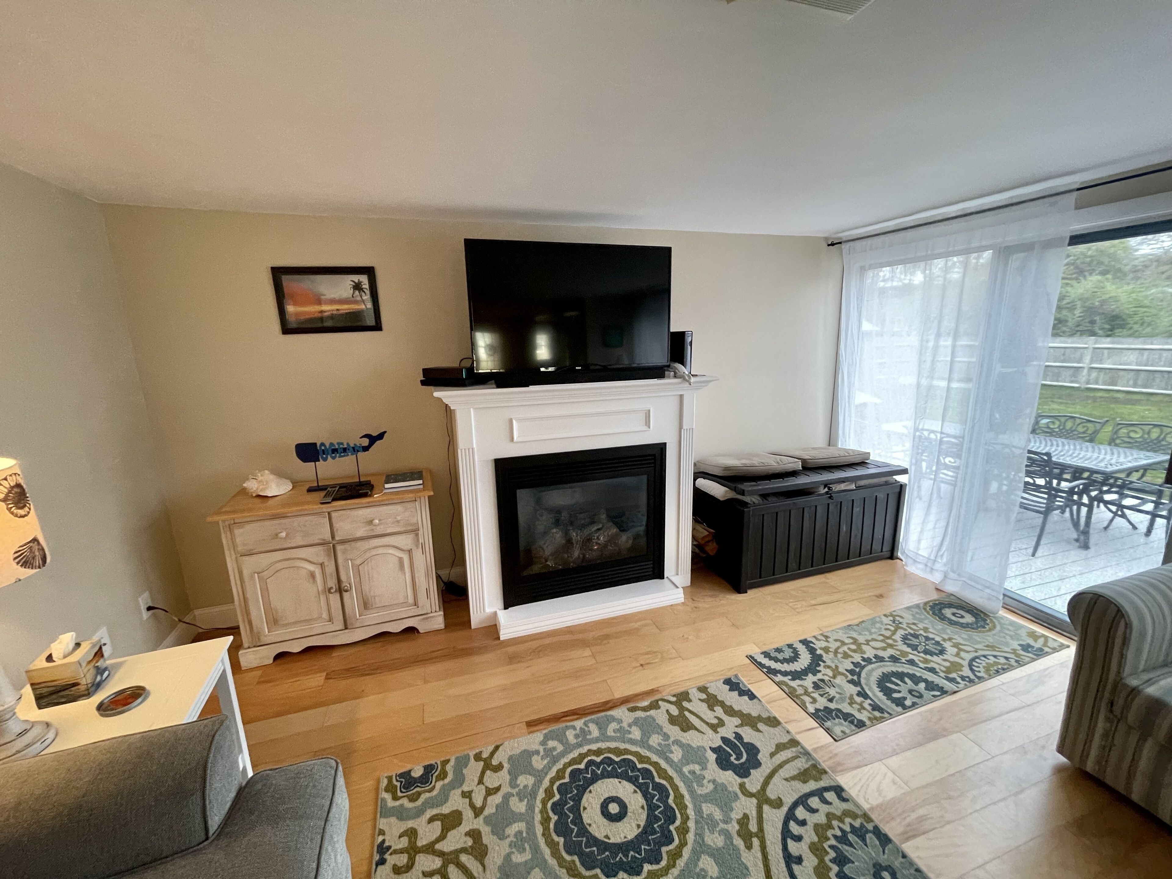A living room with a fireplace, a television mounted above it, a sofa, a coffee table, and a patterned rug.