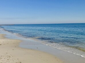 A beach with clear blue water and a sandy shore.