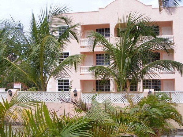 A multi-story building with balconies, surrounded by palm trees.