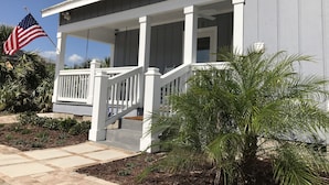 A house with a porch, a flag, and a palm tree. - 4 Bdrm/3 Bath The Tatum House Cottage - Direct Oceanfront (New Smyrna Beach)