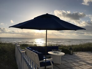 Une terrasse avec des sièges, une table et un parasol, le tout offrant une vue sur l’océan.