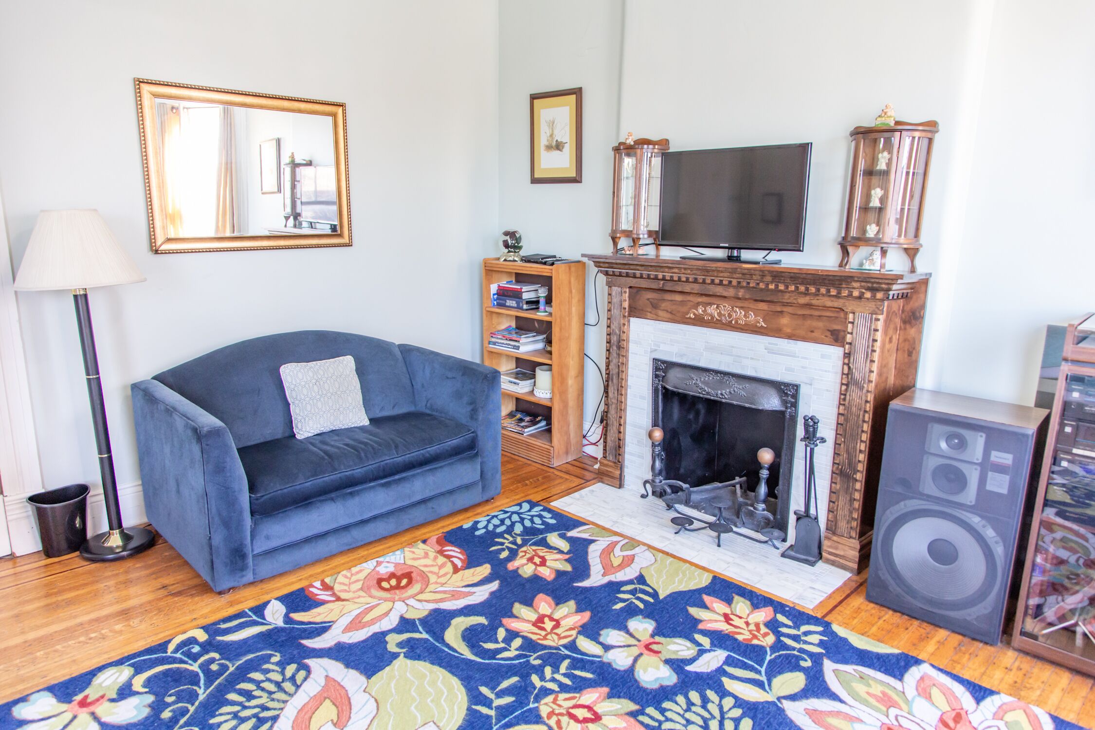 A living room with a blue sofa, a fireplace, a television, and a bookshelf.