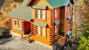 A log cabin with a green roof, wooden exterior, and a small porch. - SmokyMountainHigh: Pets, Hot Tub, Wifi, Resort Pool, Theater, Games, Fire Pit (Pigeon Forge)