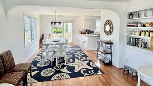 A spacious living area with a dining table, chairs, and a patterned rug. - Cape May Vacation Rentals-1 block to beach & 2  to town! Walk everywhere! (Cape May)