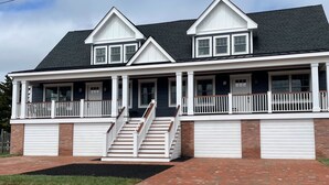 A two-story house with a front porch, a staircase, and two garage doors. - Cape May Vacation Rentals-1 block to beach & 2  to town! Walk everywhere! (Cape May)