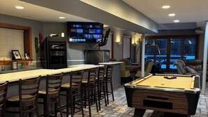 A bar area with a pool table and seating.