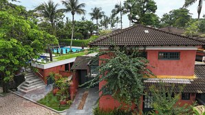 Un bâtiment rouge avec un toit en tuiles, une piscine et un escalier menant à un balcon.