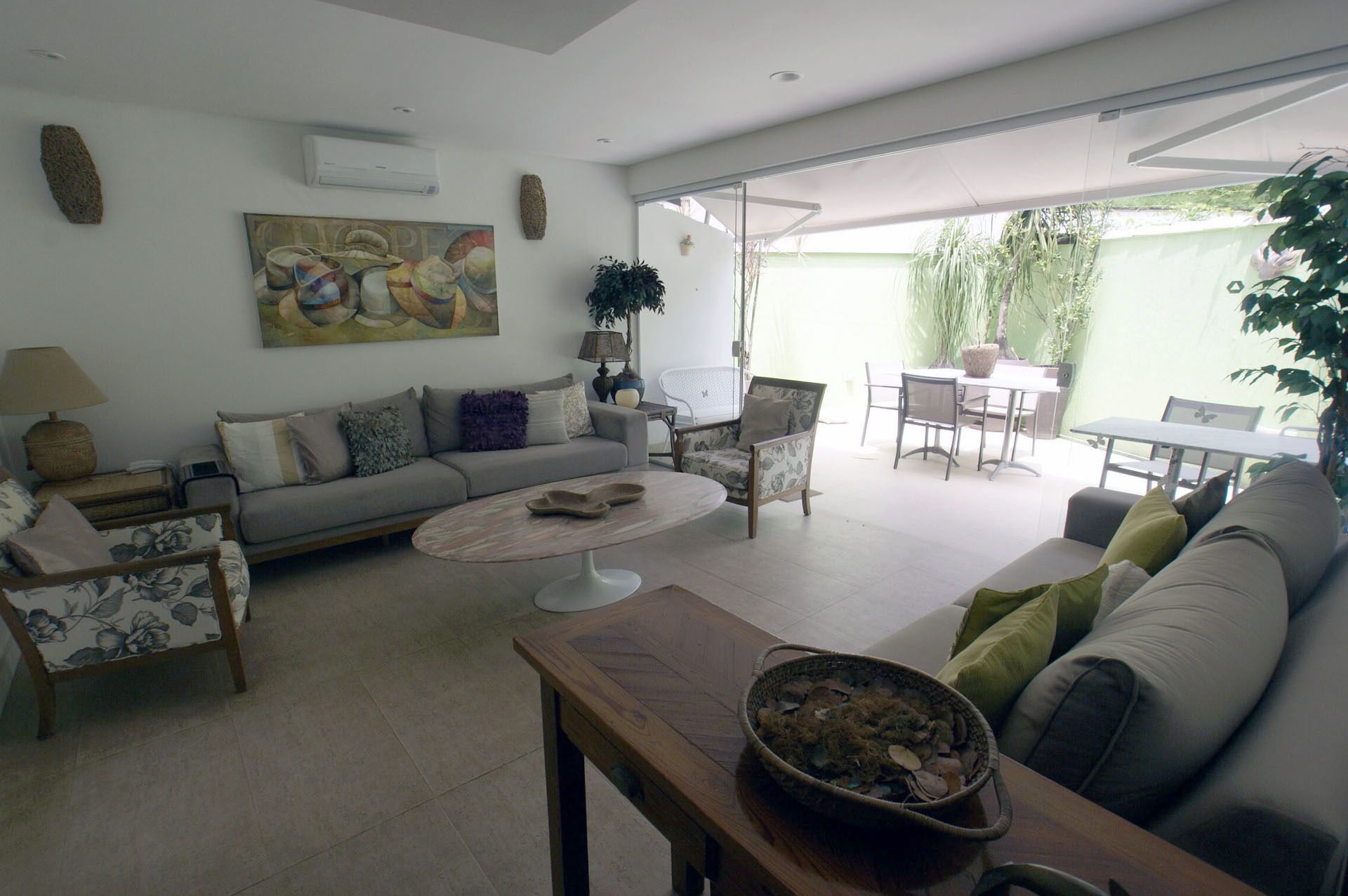 A living room with a sofa, coffee table, and chairs, a dining area with a table and chairs, and a view of the outside.