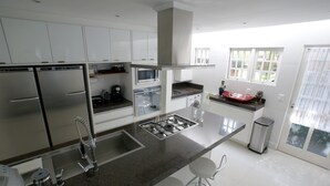Une cuisine moderne dotée d’appareils électroménagers en acier inoxydable, de meubles blancs et d’un grand îlot central avec des tabourets de bar.