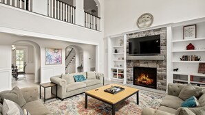 A spacious living room with a high ceiling, a fireplace, and a staircase leading to an upper level. - Luxury Lakefront Estate on Lake Anna 8,000 SqFt, Private Beach & Dock, Sleeps 20 (Bumpass)