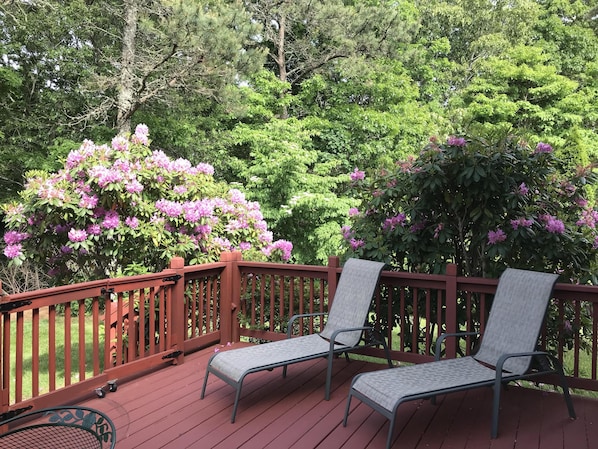 A wooden deck with two metal chairs and a small table.