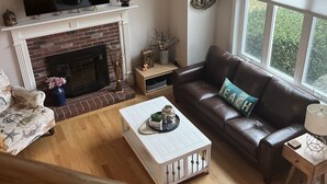 A living room with a fireplace, a television, a sofa, and a coffee table. - Charming Classic Cape Home Bordering Bike Trail-Family Friendly In Harwich (Harwich)