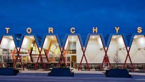 Un edificio moderno con lettere illuminate che formano la scritta "TORCHYS" sulla facciata.