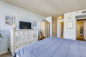 A bedroom with a bed, dresser, television, and artwork on the wall.